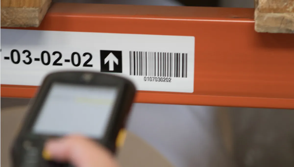 Étiquette gravée code-barres sur rayonnage d'entrepôt, scanner portable en action