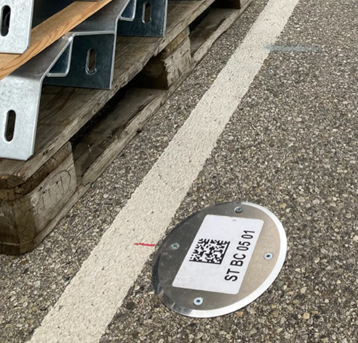 Étiquette gravée avec QR code collée sur sol béton pour traçabilité terrain en entrepôt